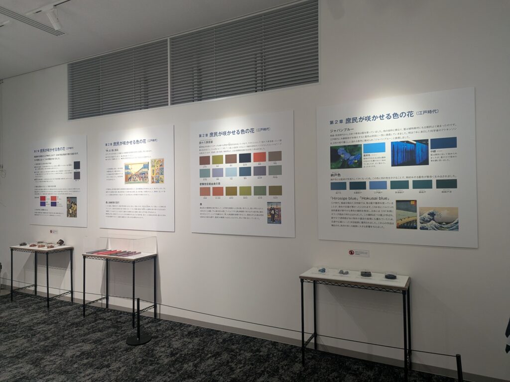 Exhibit wall with large Japanese informational panels and glass display cases below.