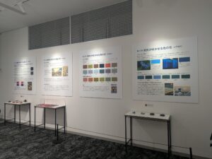 Exhibit wall with large Japanese informational panels and glass display cases below.